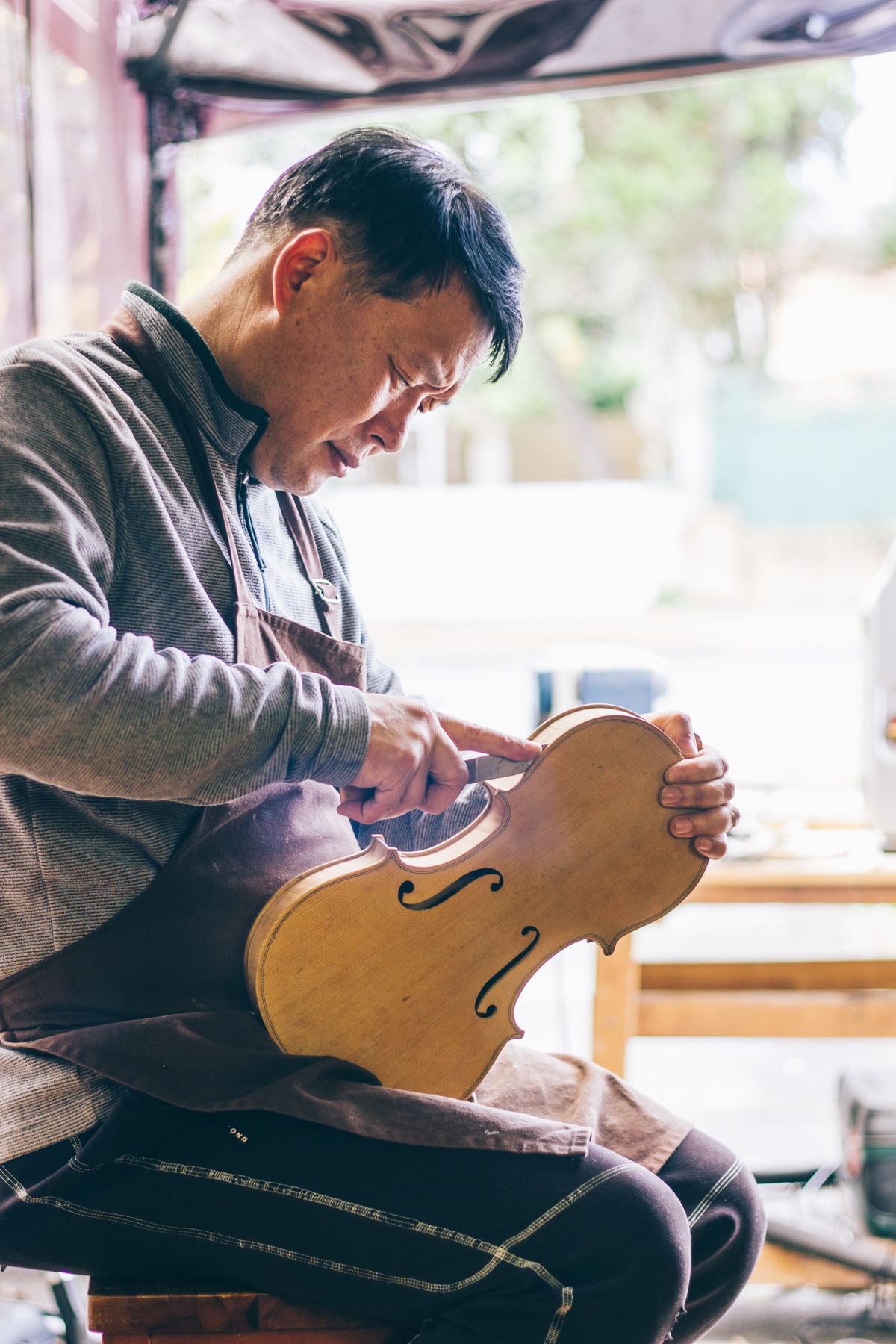 Luke carving a violin top in the String Medic workshop
